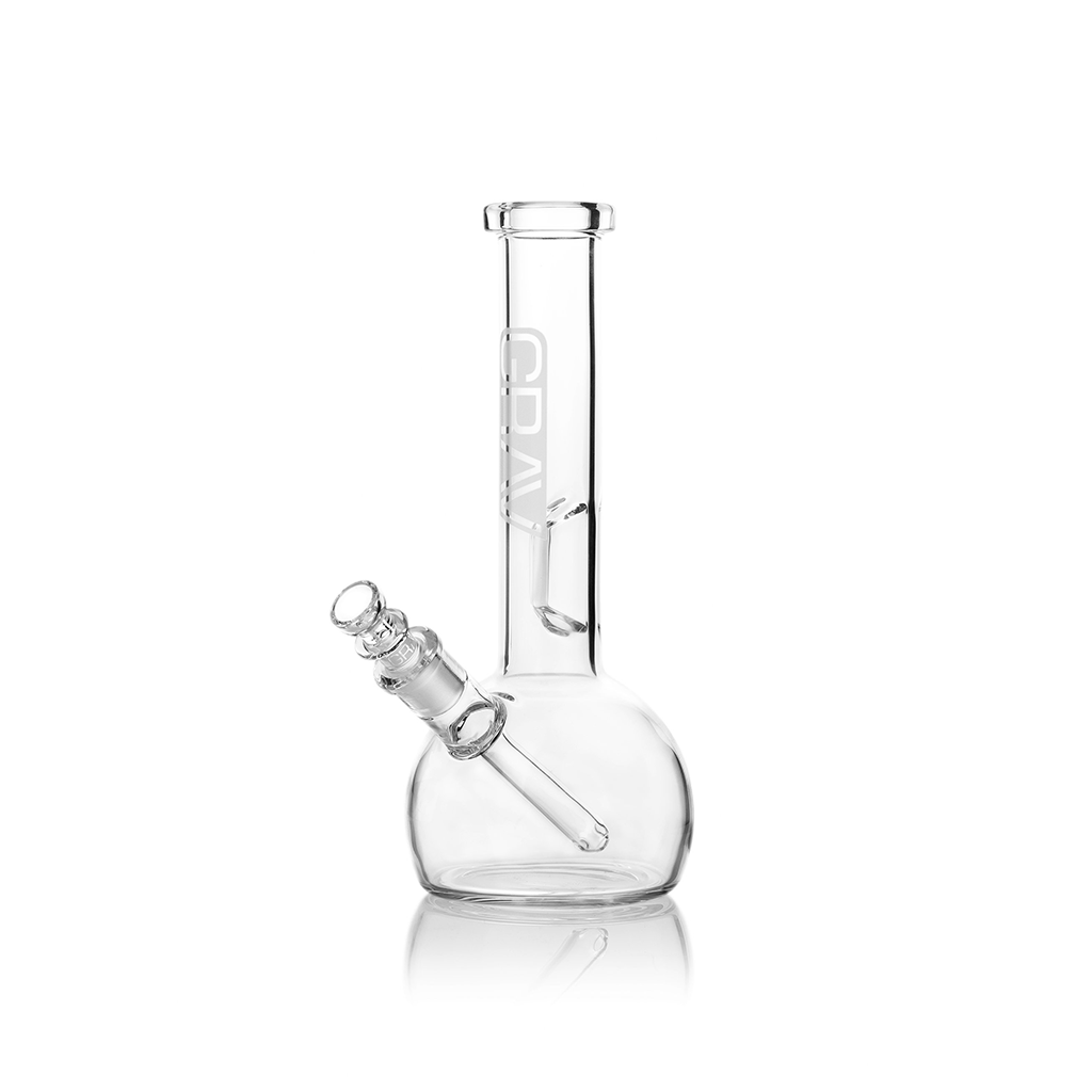 Small Round Base Bong on a table with cannabis leaves around.
